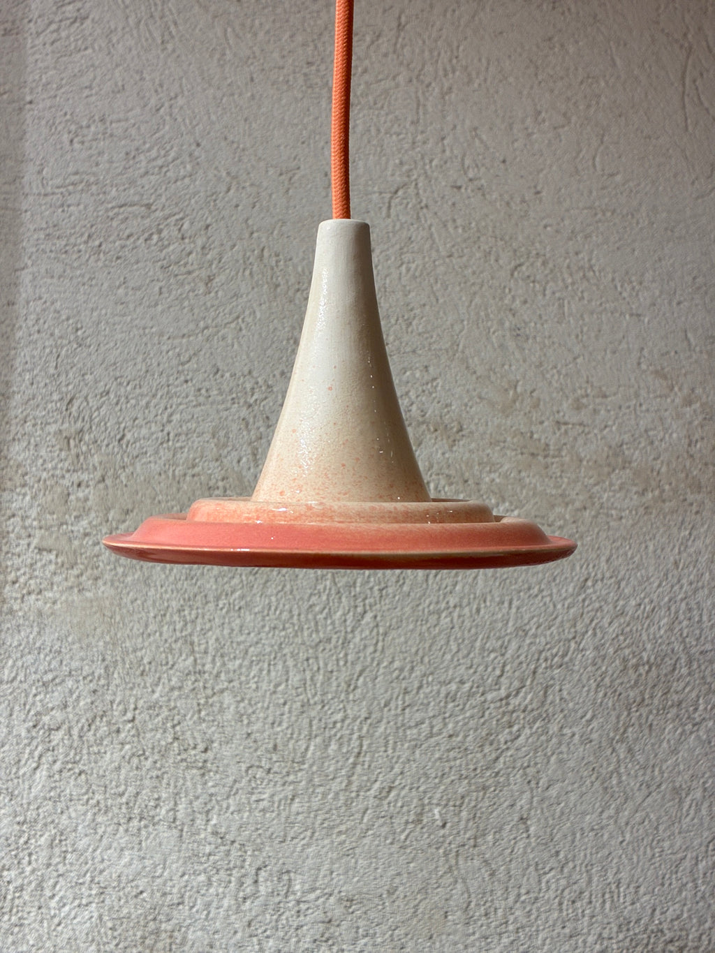  Suspension Ondine Rose Grasse et Beige Pierre, vue de profil avec câble pêche devant un mur gris.
